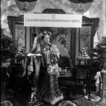 Putting a flower in her Manchu-style coiffure.  Cixi took great care of her appearance.  She designed her clothes and jewellery and supervised the making of cosmetics such as rouge, perfume and soap.  In the background, apples from her orchard were on display for their subtle fragrance.